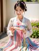 A woman in a pink and blue hanbok holding a fan.