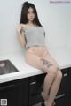 A woman sitting on top of a kitchen counter next to a sink.