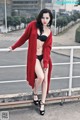 A woman in a red cardigan and black bikini posing on a bridge.