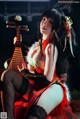A woman in a red dress sitting on a chair holding a musical instrument.