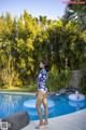 A woman in a blue and white bathing suit standing by a swimming pool.