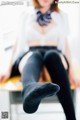 A woman sitting on top of a desk with her legs crossed.