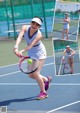 A woman in a white dress playing tennis on a court.