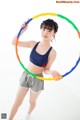 A young woman holding a hula hoop in her hands.