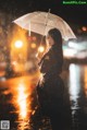 A woman standing in the rain holding an umbrella.